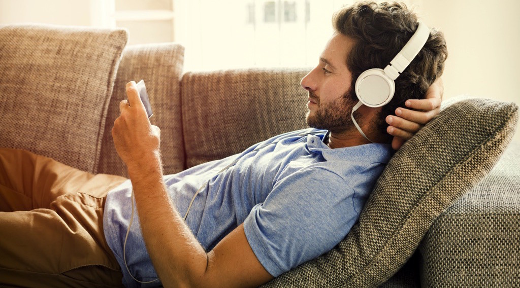 Hombre acostado en un sillón, escuchando música