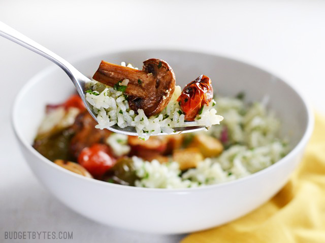 Tazón lleno con champiñones, pimiento verde, calabacita, tomates, cebolla morada y arroz blanco