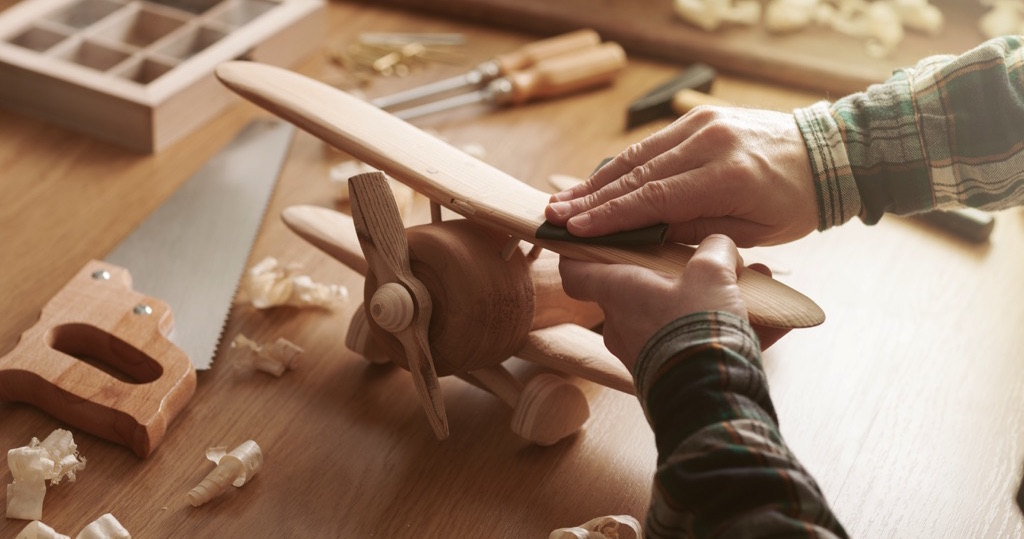 Hombre puliendo un avión de madera