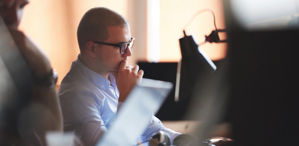 Hombre adulto calvo con lentes mirando su computadora