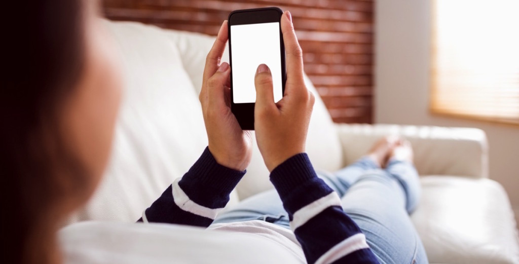 mujer acostada en un sofá mirando su celular 