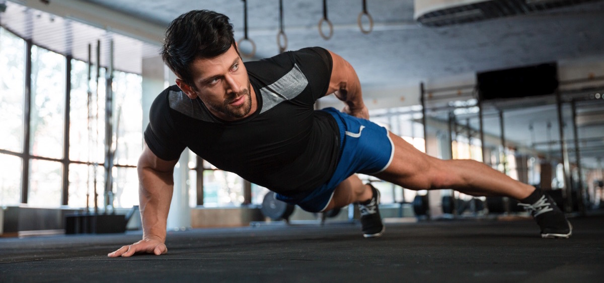 Hombre haciendo ejercicio en un gimnasio usando solo una mano