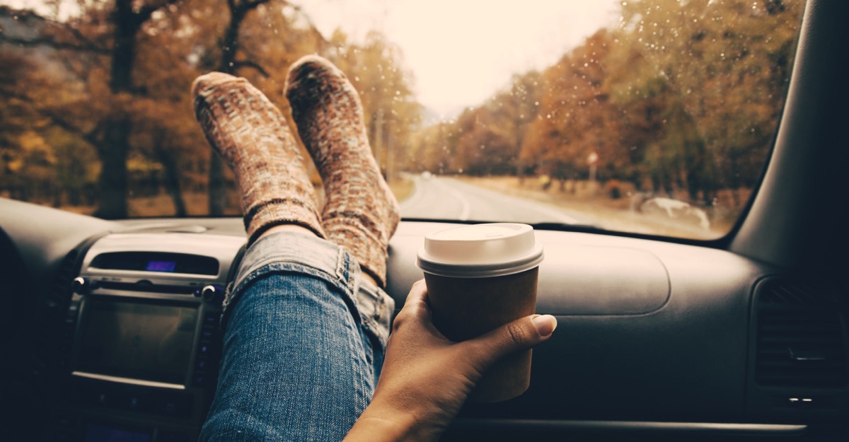 Mujer adentro de un carro, relajada con los pies estirados sobre un tablero