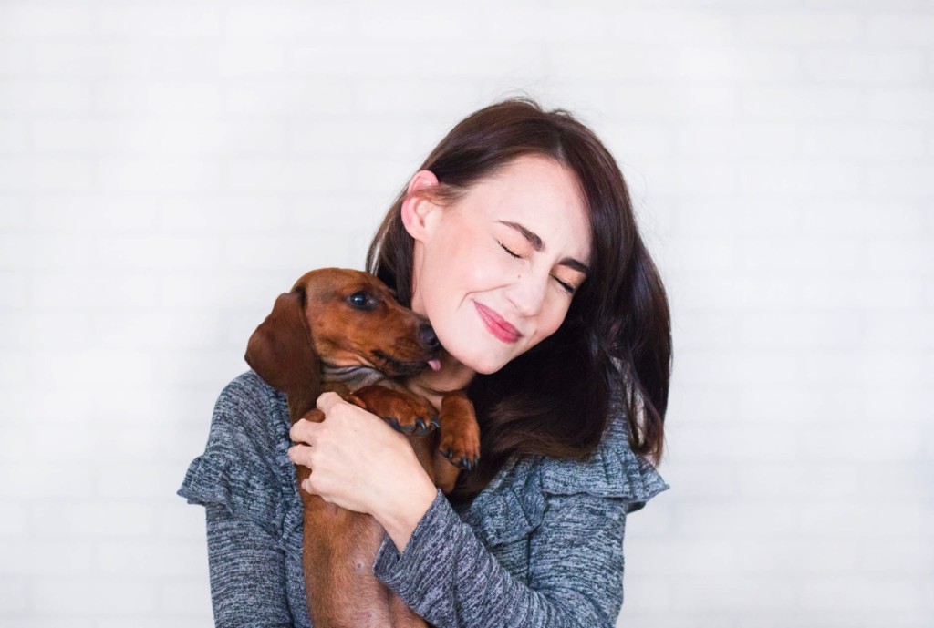 Mujer sonriendo y abrazando a perro salchicha